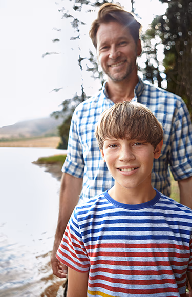 A father lifting his young son joyfully in the air during golden hour