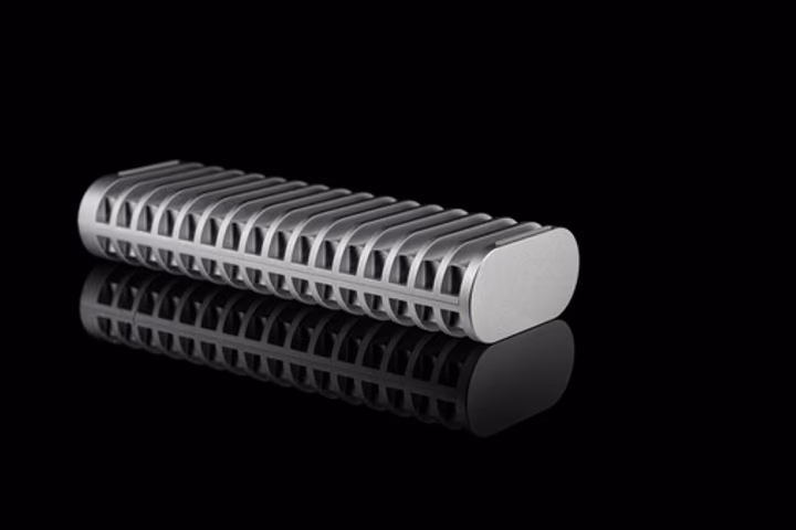 Close-up product shot of a cylindrical metal component with deep linear grooves along its surface