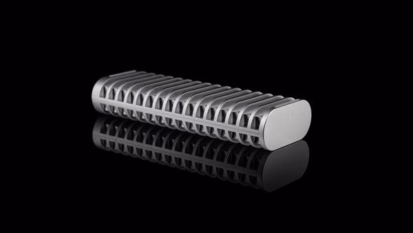 Close-up product shot of a cylindrical metal component with deep linear grooves along its surface