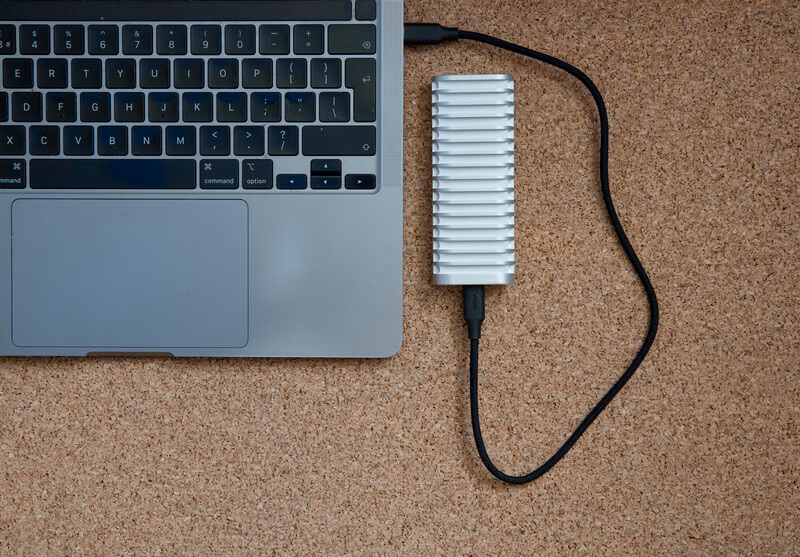 Laptop and external hard drive with cooling fins on cork surface